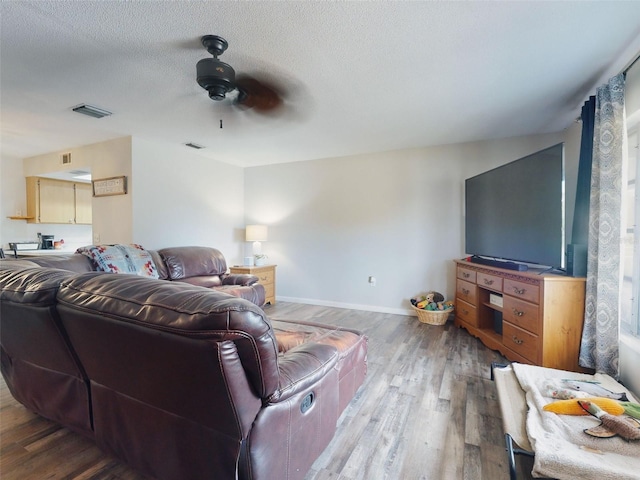 living room featuring ceiling fan, hardwood / wood-style floors, and a textured ceiling