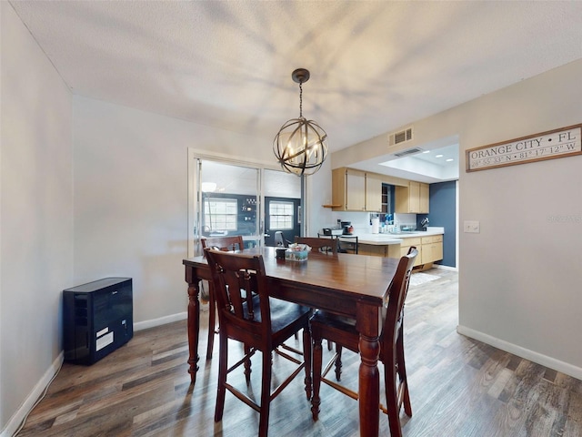 dining area featuring wood-type flooring, a textured ceiling, and an inviting chandelier