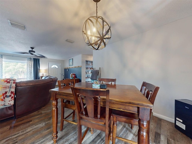 dining room with a textured ceiling, ceiling fan with notable chandelier, and dark wood-type flooring