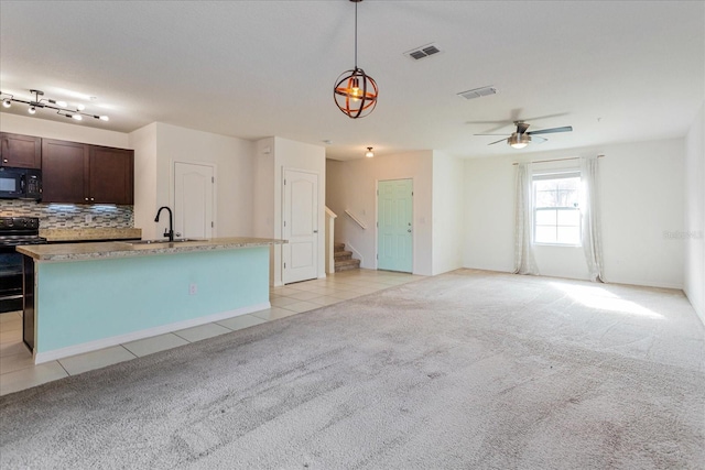 kitchen with pendant lighting, black appliances, tasteful backsplash, light colored carpet, and dark brown cabinetry