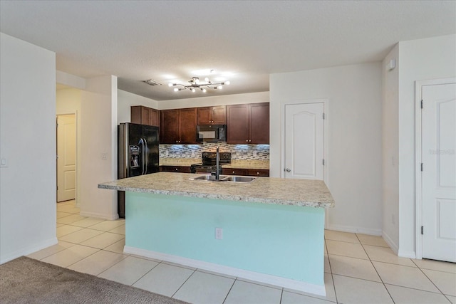 kitchen featuring black appliances, sink, an island with sink, light tile patterned flooring, and dark brown cabinetry