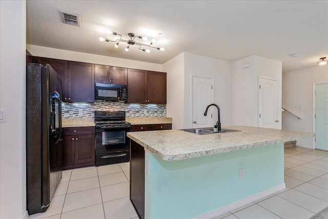 kitchen with decorative backsplash, a kitchen island with sink, sink, black appliances, and light tile patterned floors