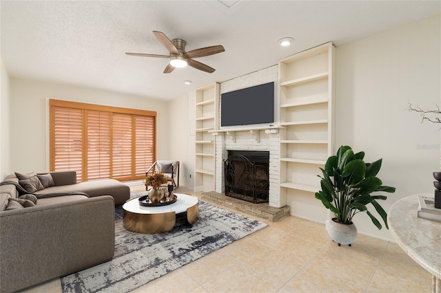 living room featuring built in shelves, ceiling fan, a textured ceiling, a fireplace, and light tile patterned floors