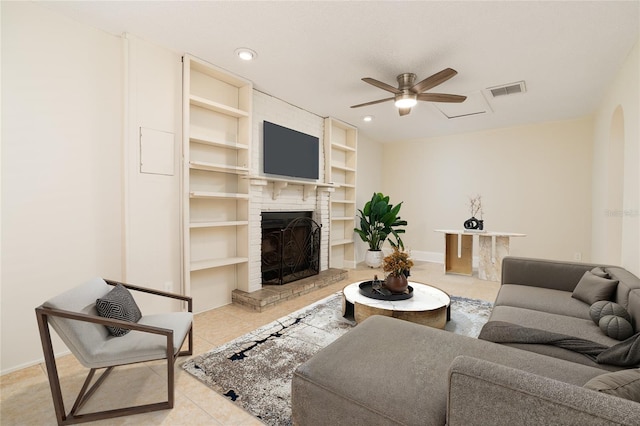 living room featuring ceiling fan, built in features, light tile patterned floors, and a brick fireplace