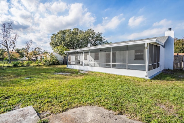 back of property with a lawn and a sunroom