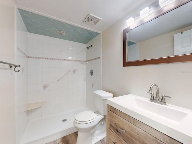 bathroom with hardwood / wood-style floors, vanity, toilet, and a tile shower