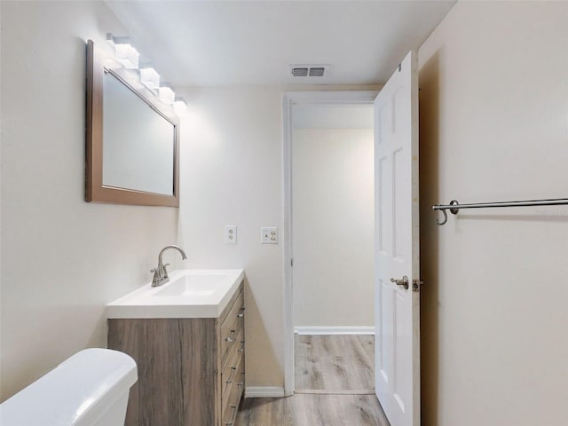 bathroom with vanity, hardwood / wood-style flooring, and toilet