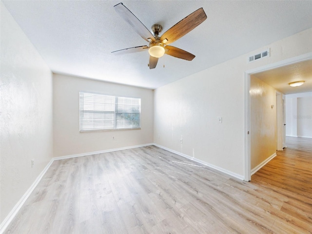 empty room with ceiling fan, light hardwood / wood-style flooring, and a textured ceiling