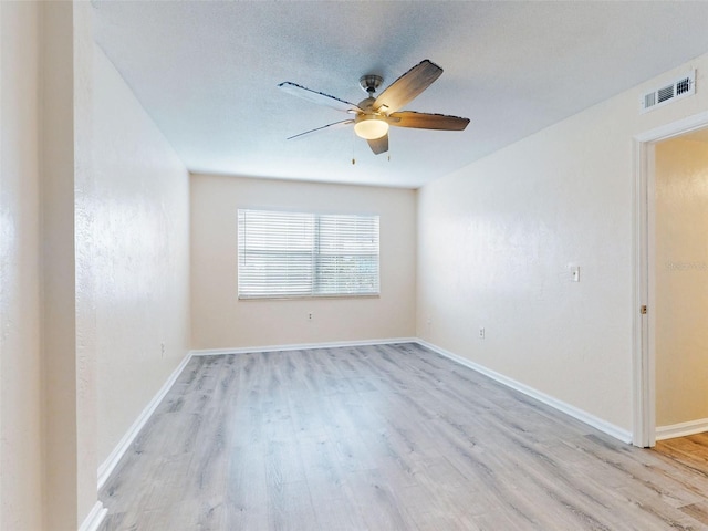 spare room featuring a textured ceiling, light wood-type flooring, and ceiling fan