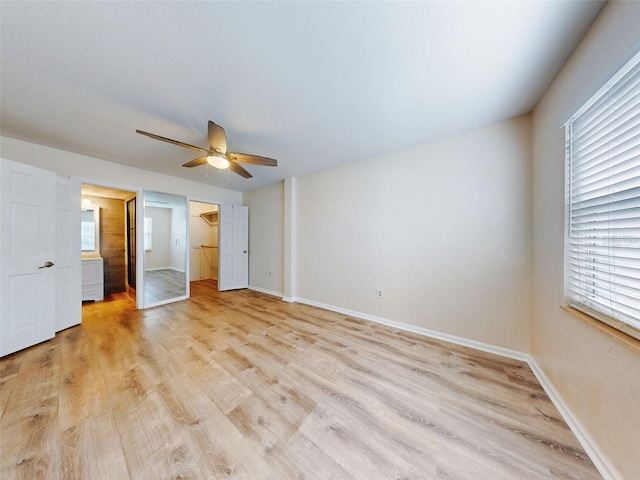 unfurnished bedroom featuring ceiling fan, light wood-type flooring, a spacious closet, and a closet