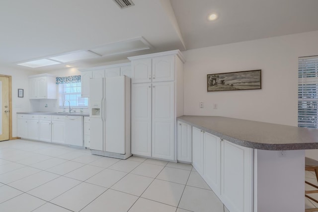 kitchen featuring kitchen peninsula, white appliances, white cabinets, and a breakfast bar