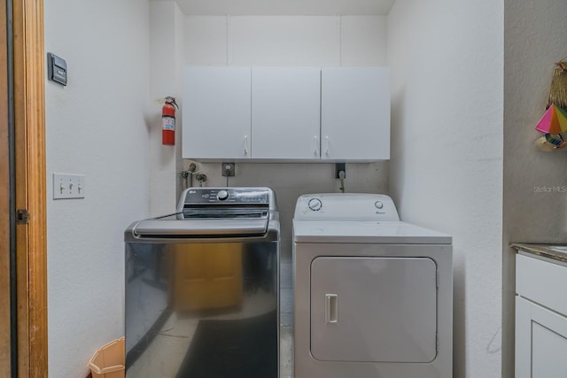 washroom with washer and clothes dryer and cabinets