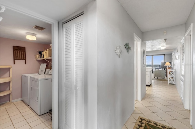 corridor with washer and clothes dryer and light tile patterned floors