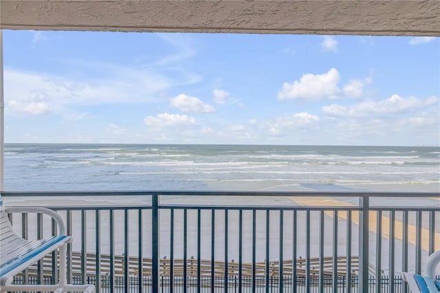 balcony with a water view and a view of the beach