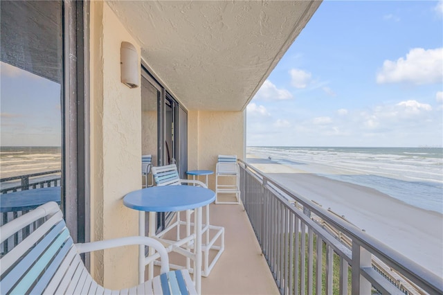 balcony featuring a water view and a view of the beach