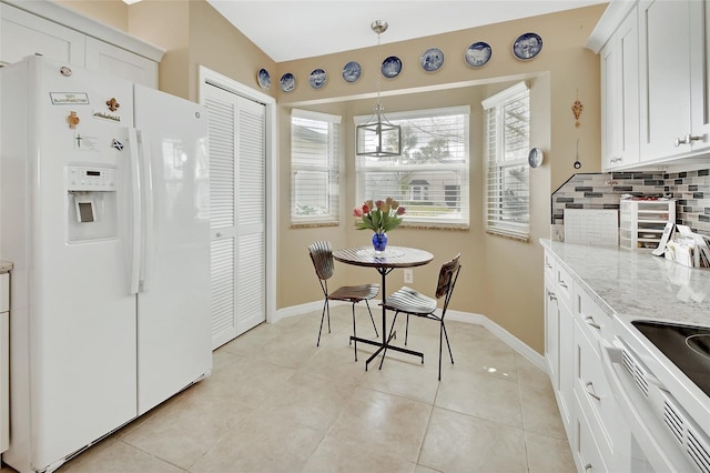 kitchen featuring backsplash, white refrigerator with ice dispenser, pendant lighting, light tile patterned floors, and white cabinetry