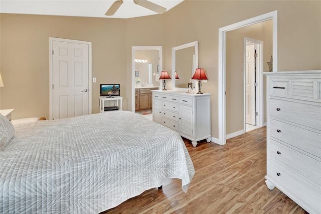 bedroom featuring light wood-type flooring, connected bathroom, vaulted ceiling, and ceiling fan