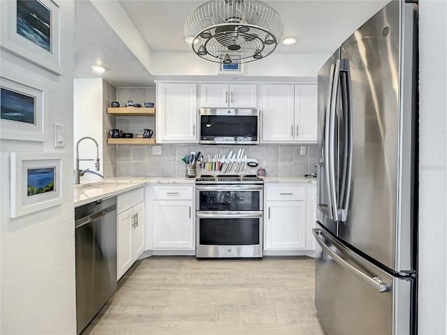 kitchen featuring white cabinets, backsplash, stainless steel appliances, and sink