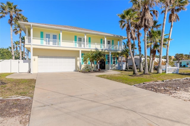 raised beach house featuring a balcony, french doors, a front lawn, and a garage