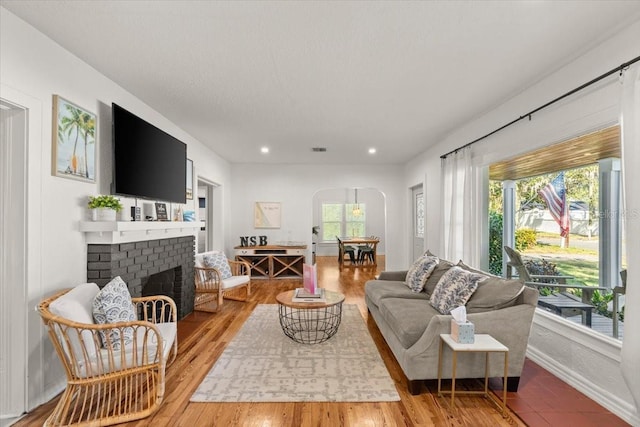 living room with hardwood / wood-style floors and a brick fireplace