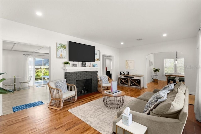 living room with hardwood / wood-style flooring and a brick fireplace