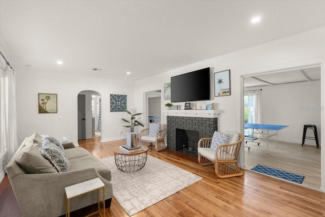 living room with a brick fireplace and hardwood / wood-style flooring