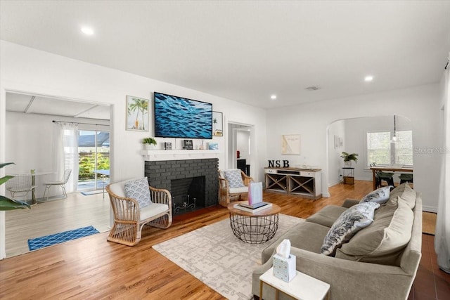 living room featuring wood-type flooring and a brick fireplace