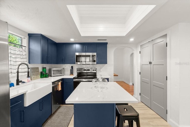 kitchen featuring stainless steel appliances, a kitchen bar, blue cabinets, and a kitchen island