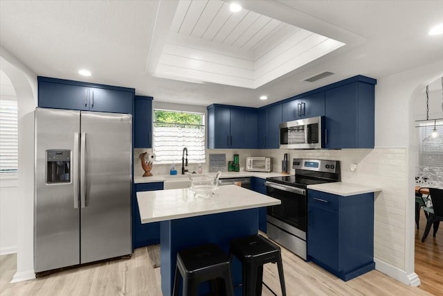 kitchen featuring stainless steel appliances, a center island, light hardwood / wood-style floors, and blue cabinets