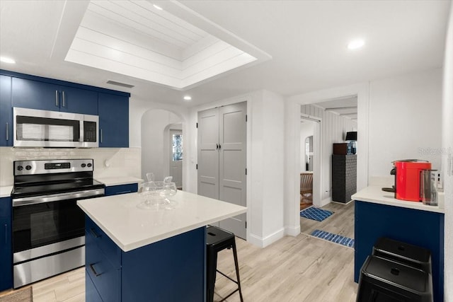 kitchen featuring blue cabinets, stainless steel appliances, light hardwood / wood-style floors, and a kitchen island