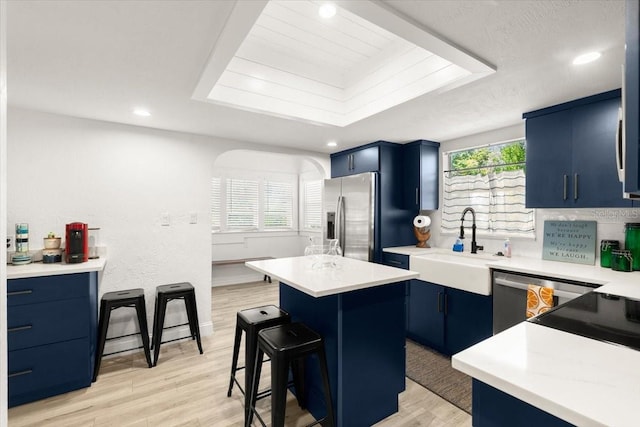 kitchen featuring light hardwood / wood-style flooring, blue cabinetry, appliances with stainless steel finishes, a kitchen island, and a kitchen bar