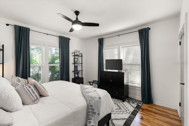 bedroom with ceiling fan, multiple windows, and light wood-type flooring