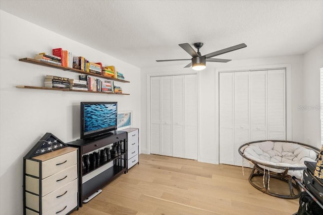 sitting room featuring ceiling fan, light hardwood / wood-style flooring, and a textured ceiling