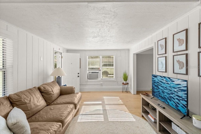 living room featuring cooling unit, a textured ceiling, and light wood-type flooring