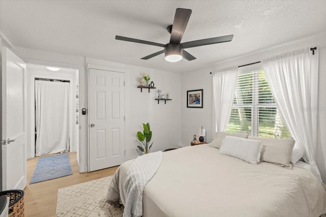 bedroom with light wood-type flooring, a textured ceiling, and ceiling fan