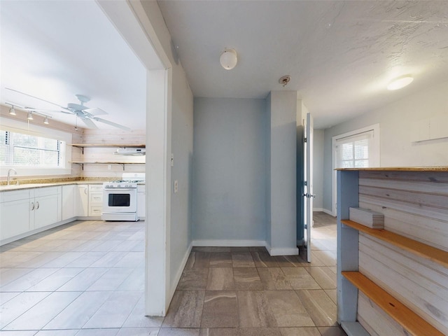 kitchen with ceiling fan, white cabinetry, gas range gas stove, and a textured ceiling