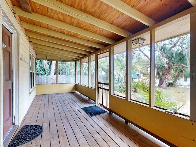 unfurnished sunroom with a healthy amount of sunlight, wood ceiling, and beam ceiling