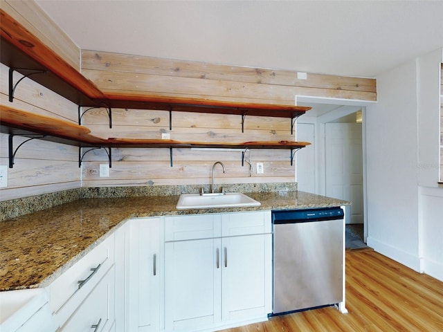 kitchen featuring stainless steel dishwasher, light hardwood / wood-style flooring, white cabinets, dark stone countertops, and sink