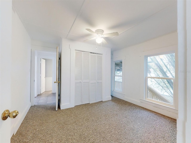 unfurnished bedroom with ceiling fan, a closet, and light carpet