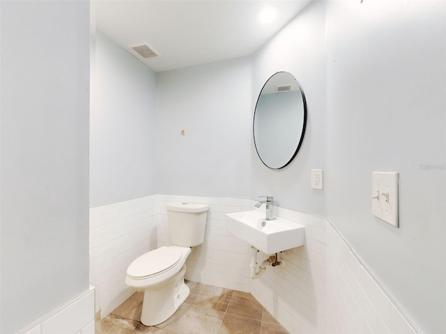 bathroom featuring toilet, tile walls, tile patterned floors, and sink