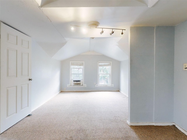 additional living space with cooling unit, vaulted ceiling, and light colored carpet