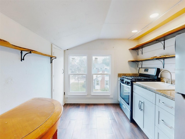 kitchen featuring vaulted ceiling, dark wood-type flooring, light stone counters, stainless steel range with gas cooktop, and white cabinets