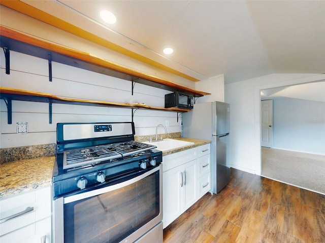 kitchen with sink, white cabinetry, lofted ceiling, light stone countertops, and appliances with stainless steel finishes