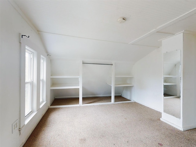 unfurnished bedroom featuring lofted ceiling, a closet, and carpet flooring