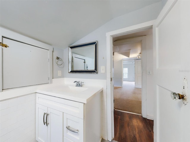 bathroom featuring hardwood / wood-style flooring, vaulted ceiling, and vanity