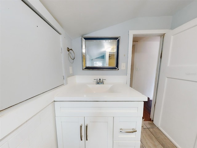 bathroom featuring wood-type flooring, vanity, and vaulted ceiling