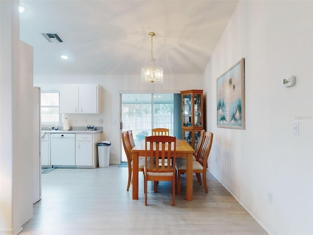 dining area with light wood-type flooring and a notable chandelier