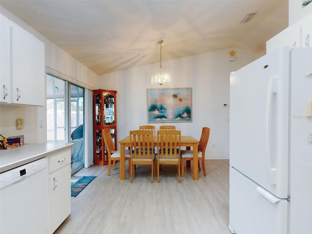 dining space with light hardwood / wood-style floors, a notable chandelier, and vaulted ceiling