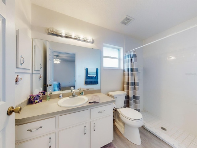 bathroom with ceiling fan, vanity, toilet, walk in shower, and hardwood / wood-style flooring