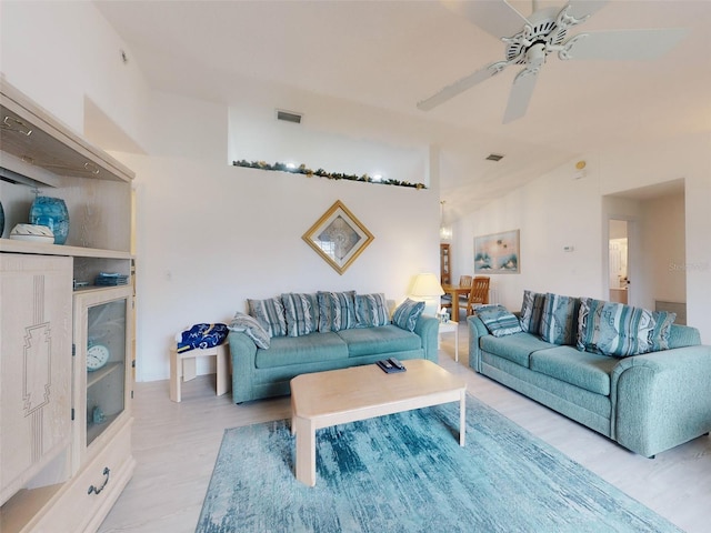 living room with vaulted ceiling, ceiling fan, and light wood-type flooring